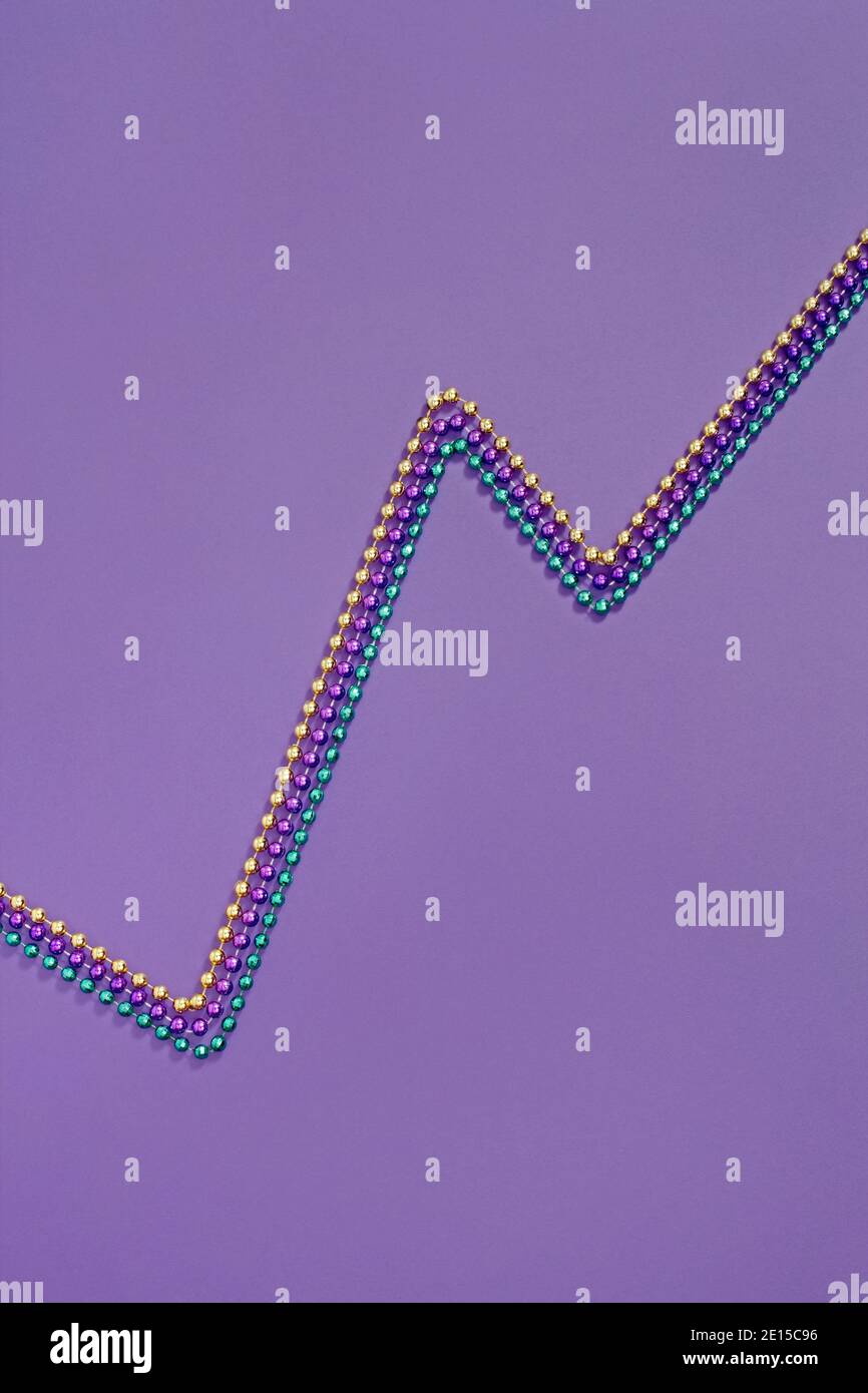 Mardi Gras Perlen in Form einer Zick-Zack-Linie fotografiert Auf einem violetten Hintergrund Stockfoto