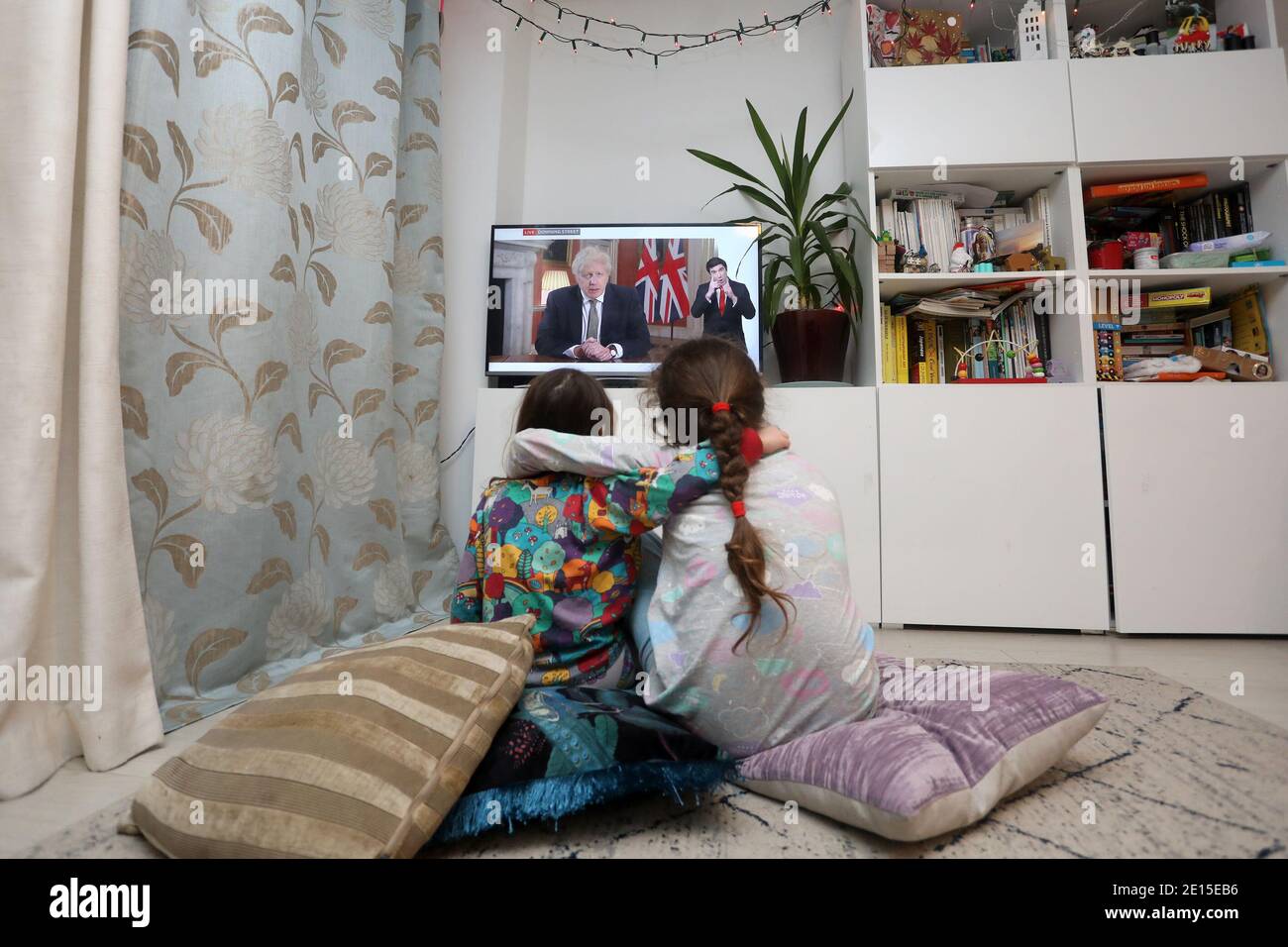 Chichester, West Sussex, Großbritannien. Florence, 5, (links) und ihre Schwester Isabelle, 8, (rechts) beobachten den britischen Premierminister Boris Johnson, der am Montag, den 4. Januar 2021 um 20 Uhr seine Rede hält und Großbritannien in seine dritte Absperrung bringt und seine Schulen schließt. Kredit: Sam Stephenson/Alamy Live Nachrichten Stockfoto