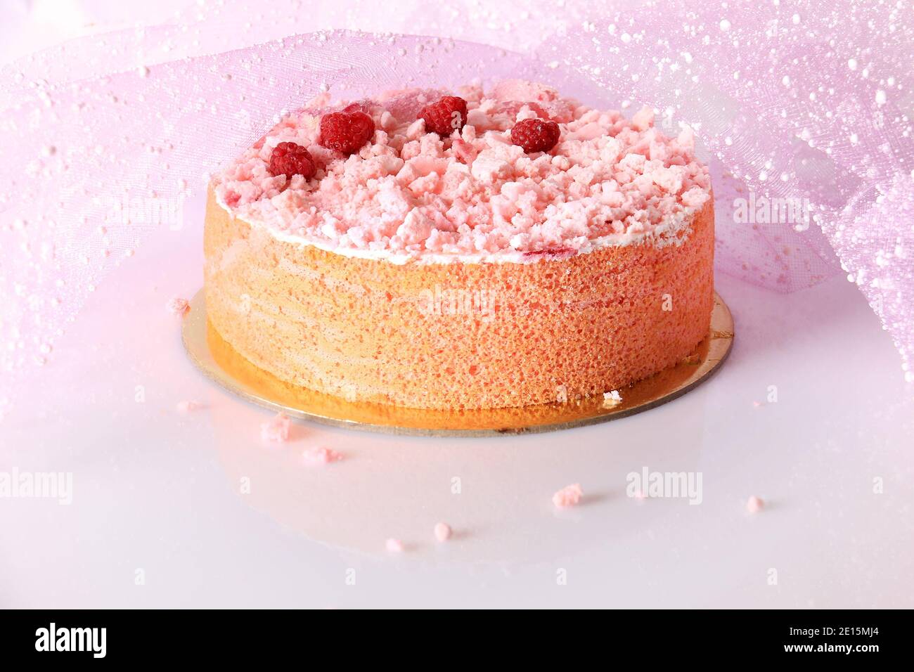 Ein rosa Kuchen mit Baiser bröckelt, Himbeeren, und zuckerhaltigen Rosenblätter. Stockfoto