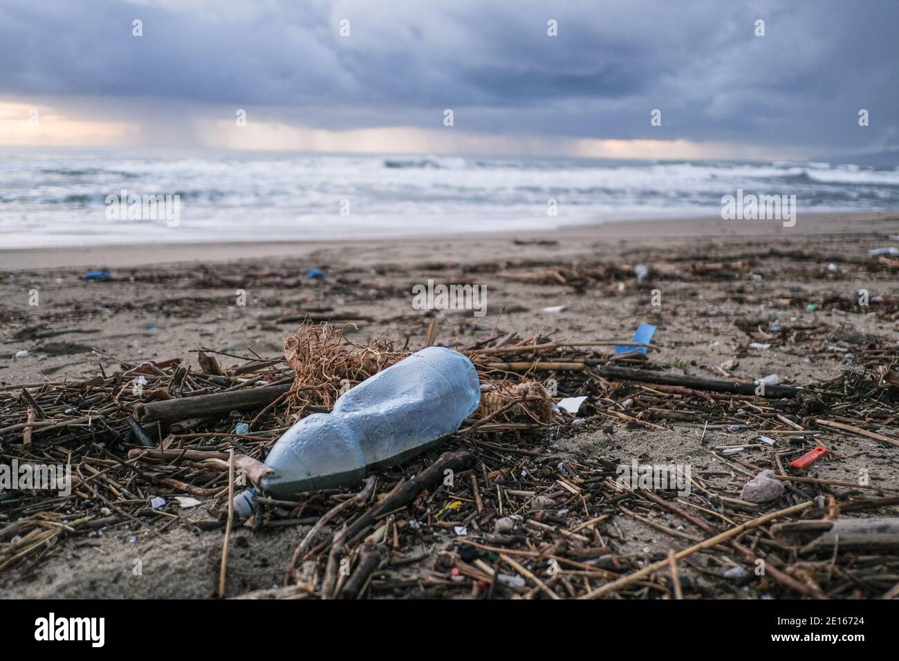 Plastikflasche auf schmutziger Müllhalde, verschmutztes Ozeanküsten-Ökosystem nach Seesturm Stockfoto