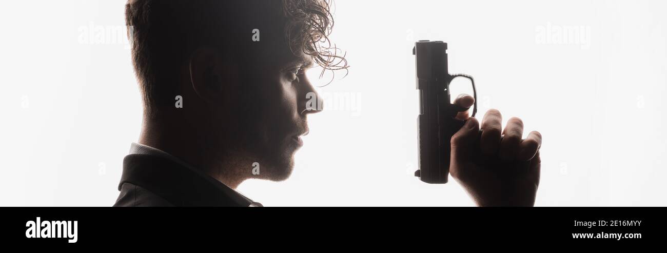 Seitenansicht des lockigen Mannes mit Waffe isoliert auf weißem Banner Stockfoto