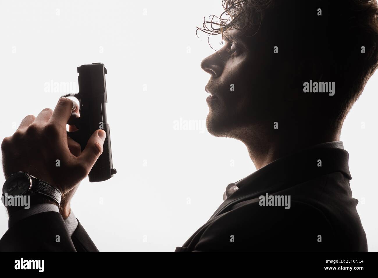Seitenansicht eines bewaffneten Mannes in formeller Kleidung mit Pistole Isoliert auf Weiß Stockfoto