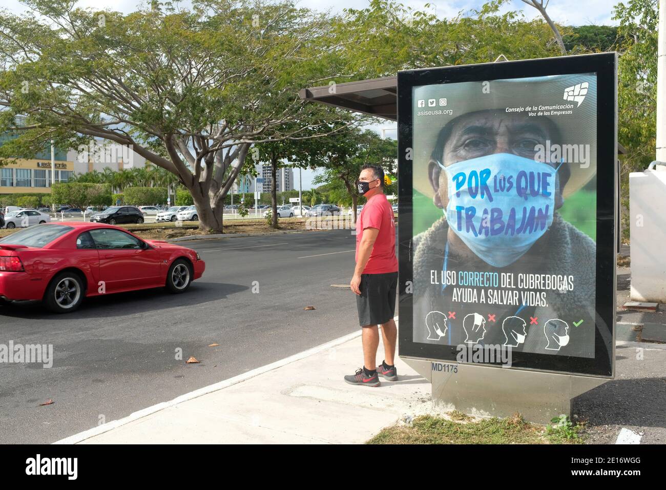 Mann wartet auf den Bus vor einer Werbung, die Menschen ermutigt, Gesichtsmasken während der Pandemie von Covid 19, Merida, Mexiko, zu tragen Stockfoto