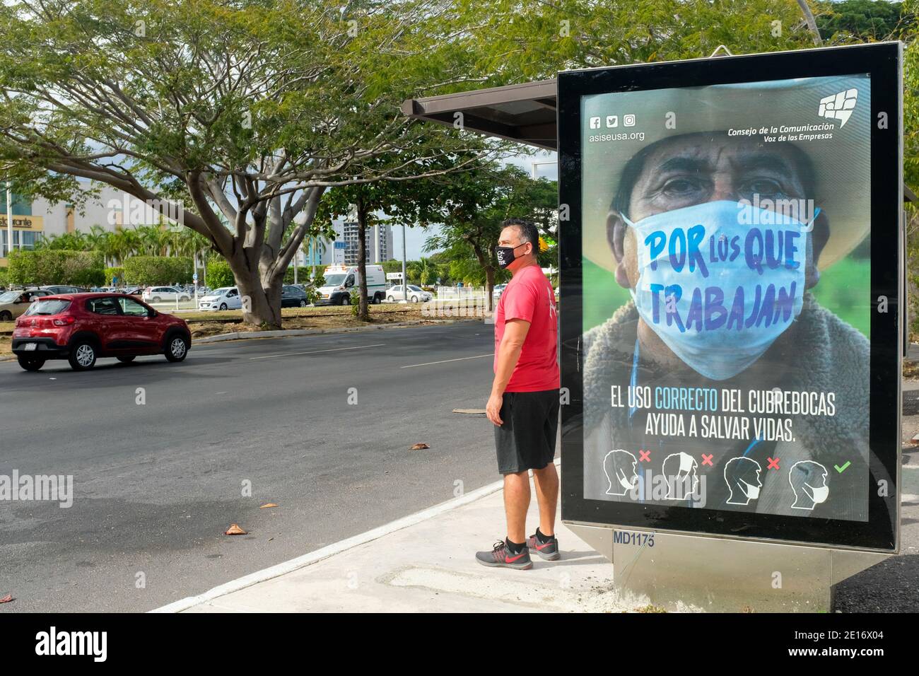 Mann wartet auf den Bus vor einer Werbung, die Menschen ermutigt, Gesichtsmasken während der Pandemie von Covid 19, Merida, Mexiko, zu tragen Stockfoto