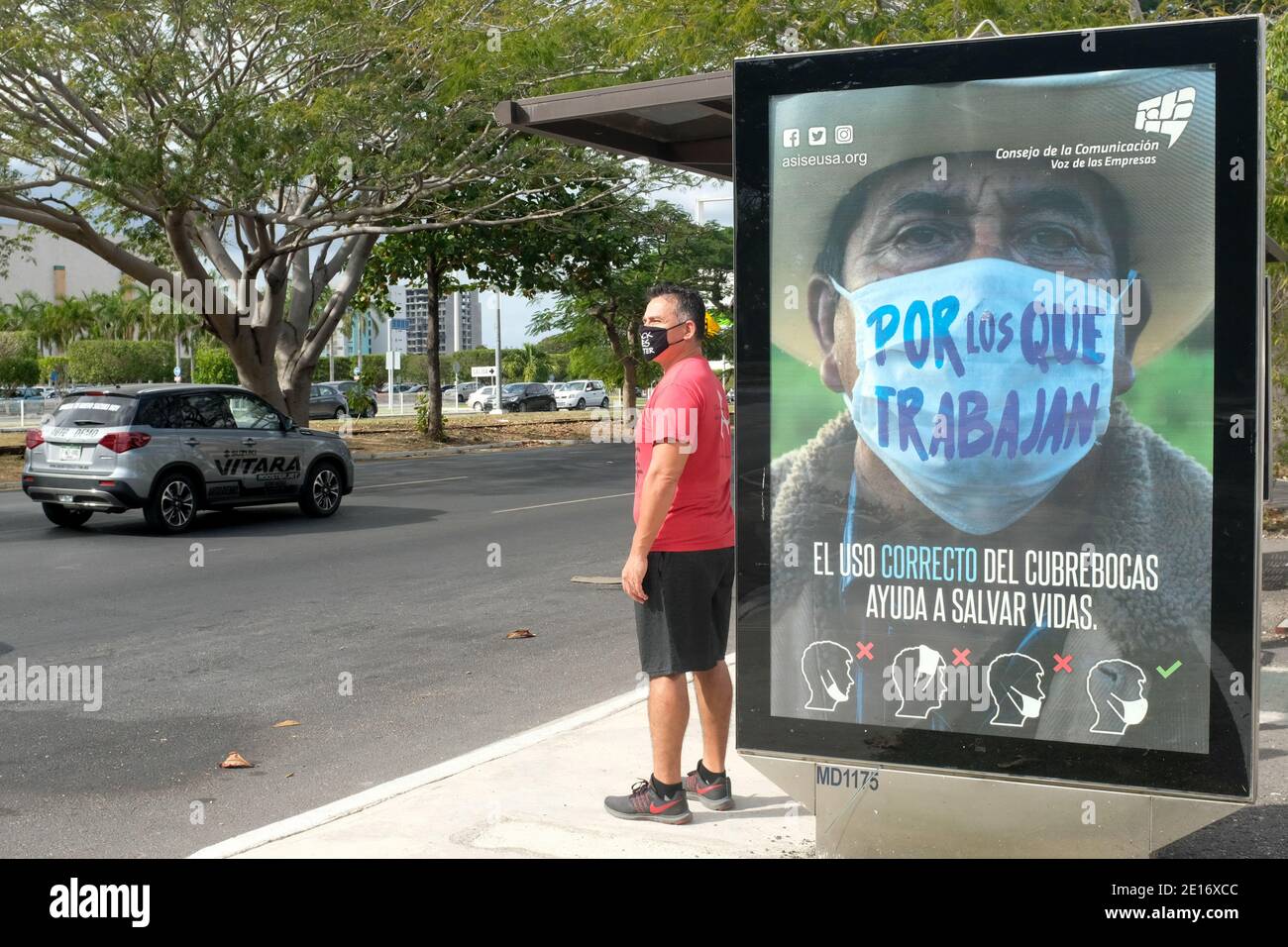 Mann wartet auf den Bus vor einer Werbung, die Menschen ermutigt, Gesichtsmasken während der Pandemie von Covid 19, Merida, Mexiko, zu tragen Stockfoto