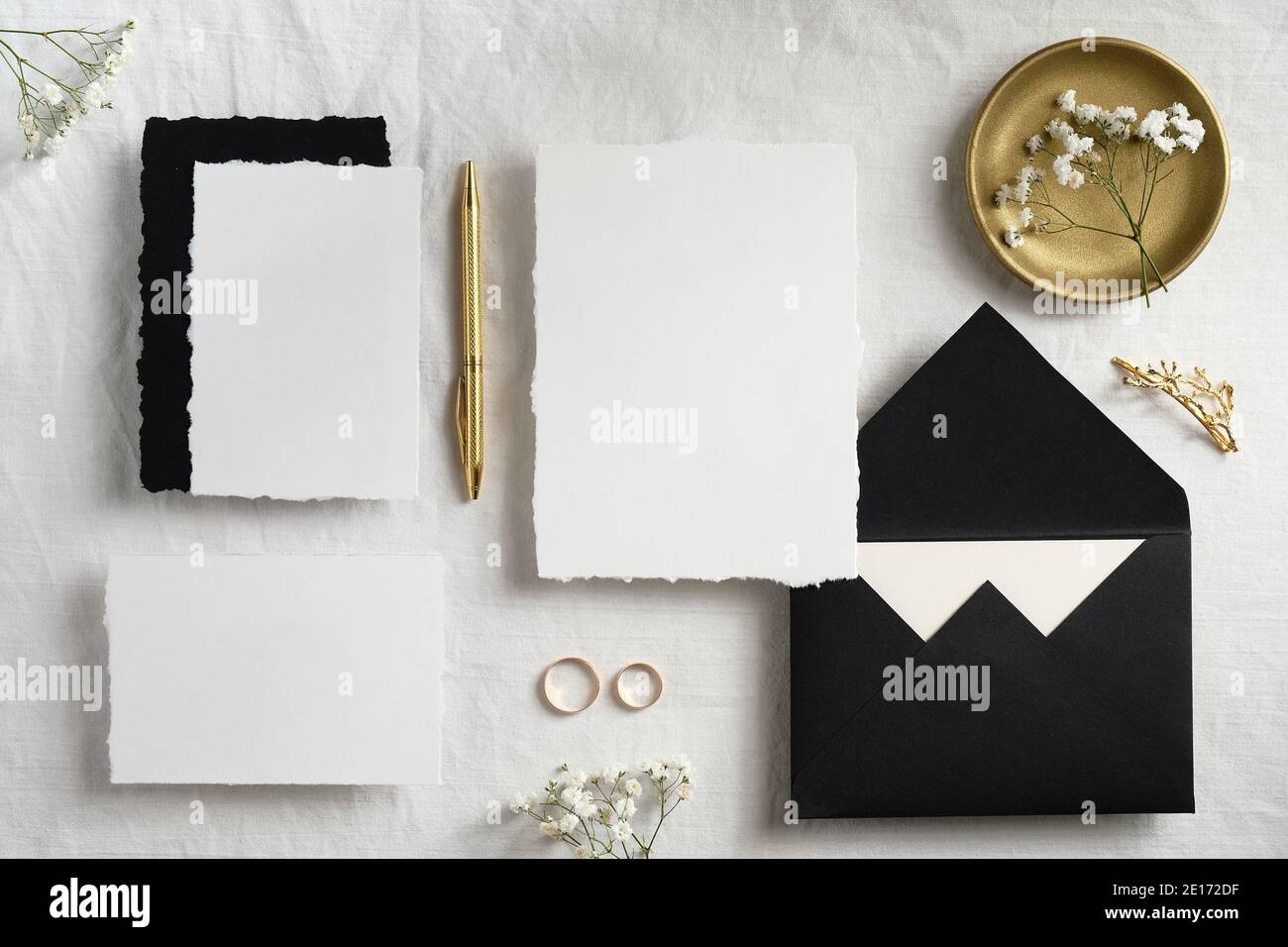 Hochzeit Schreibwaren Stillleben Szene Draufsicht. Flach legen Einladungen Karten Vorlagen, schwarze Umschläge, goldenen Stift, Ringe, Blumen auf textilen Hintergrund. Stockfoto