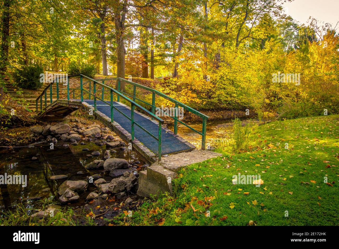 Herbst Herbst Farbe Landschaft. Kleine Fußgängerbrücke über einen Bach, umgeben von lebendiger Herbstfärbung in einem kleinen County Park in Jackson County, Michigan. Stockfoto