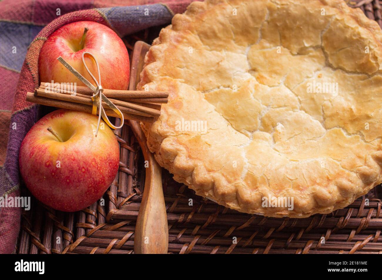 Kleine Hausgemachte Apfelkuchen. Frisch aus dem Ofen Apfelkuchen umgeben von Äpfeln und Zimtstangen mit Holzlöffel. Stockfoto