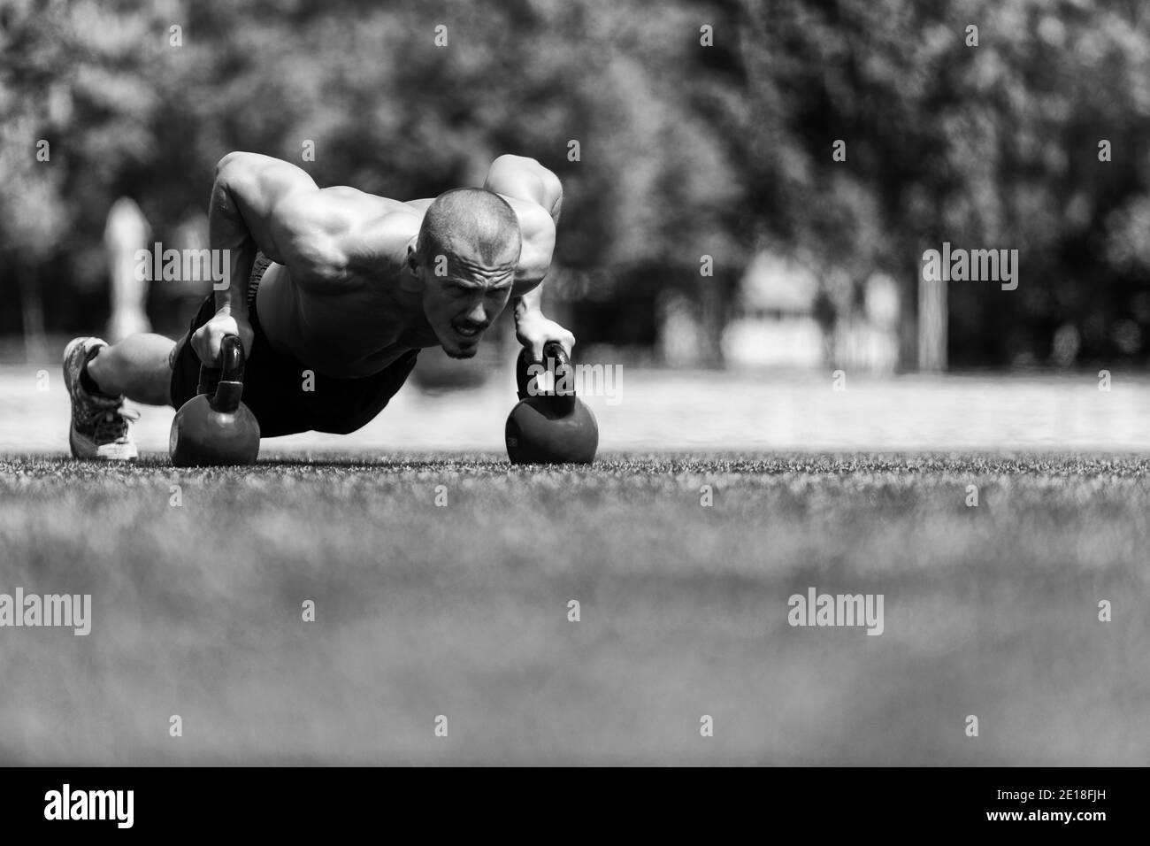 Gesunder Mann Sportler Tun Liegestütze Workout Mit Wasserkocher Glocke Im Freien - Kessel-Glocke Übung Stockfoto