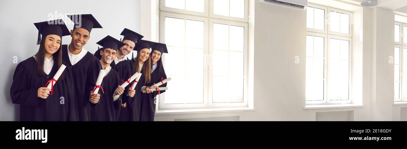 Banner mit glücklichen Absolventen halten Diplome und lächeln in der Universität Flur mit großen Fenstern Stockfoto