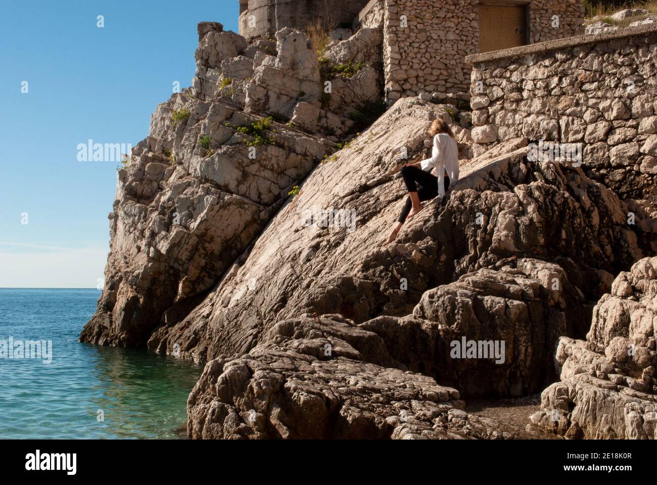 Die Frau auf den Felsen vor dem Meer. Stockfoto