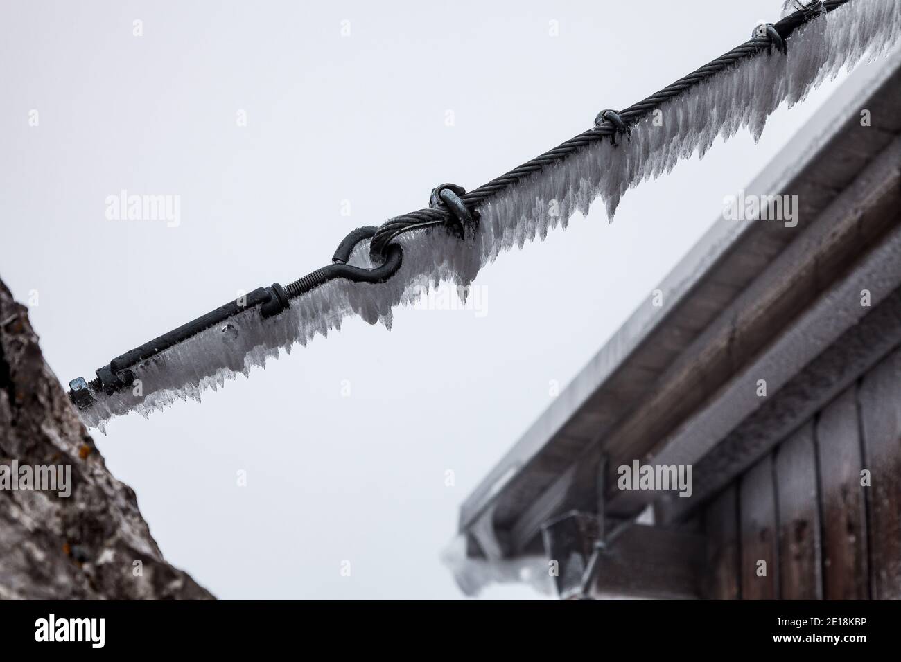Ein Nahaufnahme Foto von kleinen Eiszapfen, die an einem hängen Stahlkabel Stockfoto