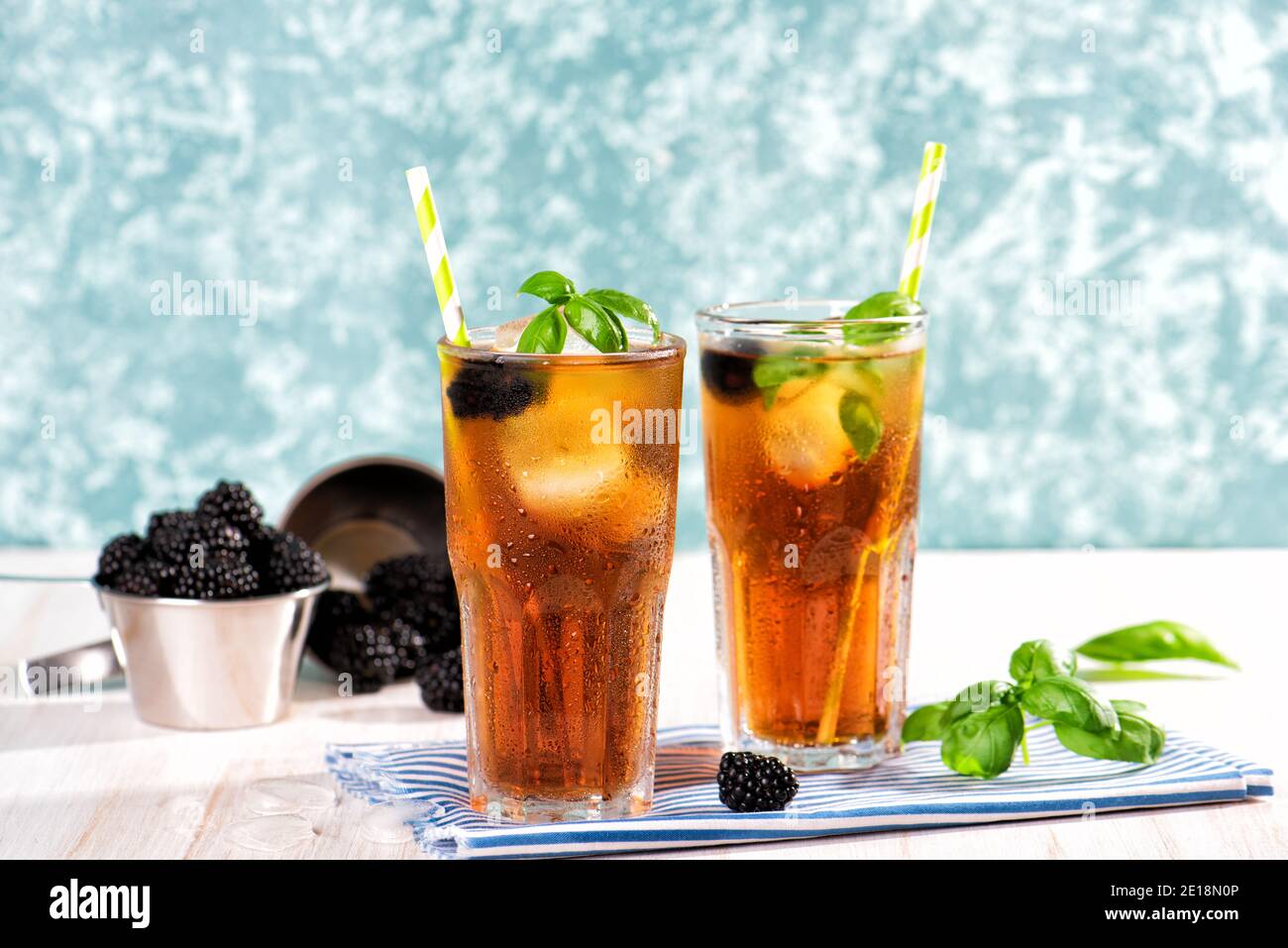 Das Glas Eistee mit Brombeere auf Holztisch. Cuba Libre oder Long Island Cocktail, kaltes Getränk oder Limonade mit Zitrone und Basilikum. Grüner Türkis Stockfoto