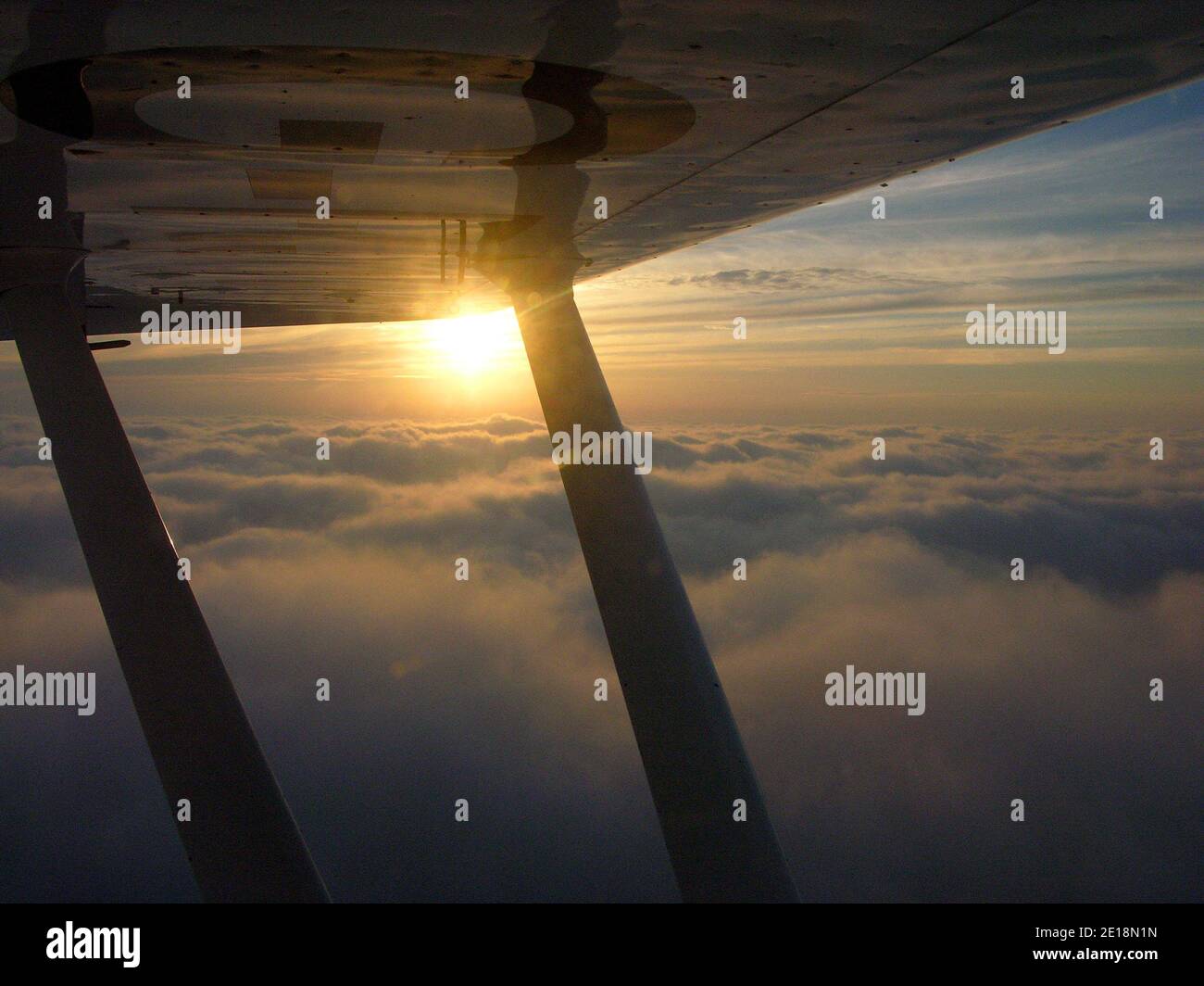 Luftaufnahme des Sonnenuntergangs unter dem Flügel eines leichten Flugzeuges (Piper PA18 Super Cub), britischer Himmel Stockfoto