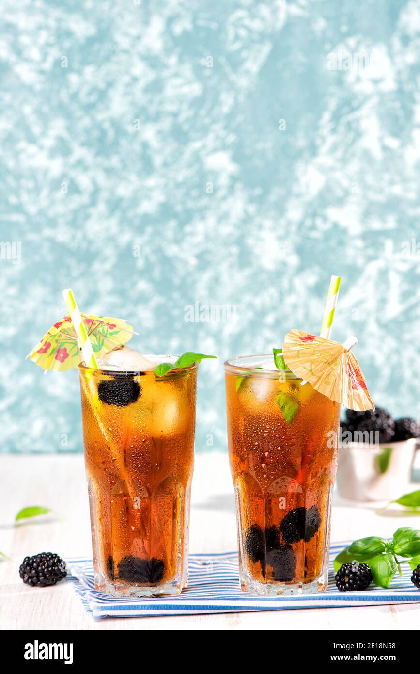 Das Glas Eistee mit Brombeere auf Holztisch. Cuba Libre oder Long Island Cocktail, kaltes Getränk oder Limonade mit Zitrone und Basilikum. Grüner Türkis Stockfoto