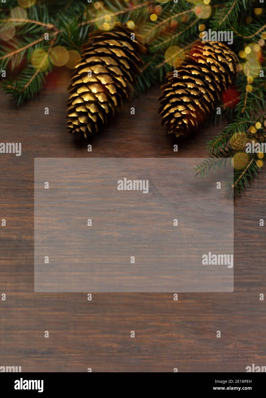 Weihnachtskarte. Tannenzweig mit goldenen Zapfen auf einer hölzernen Oberfläche. Hintergrund mit einem glasmorphen Effekt und einem Ort für Text, Kopierraum. Vertikale Sho Stockfoto