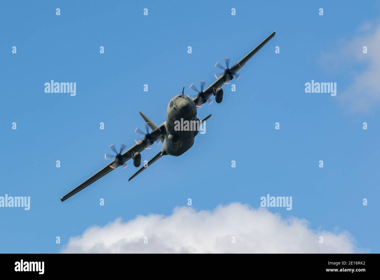 Lockheed C-130 Hercules fliegt tief in Tälern und Bergen. Grüne getarnte Truppe und Frachttransporter. Stockfoto