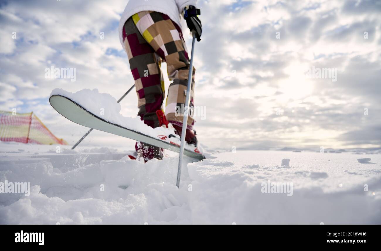 Nahaufnahme, Nahaufnahme der Beine des Skifahrers. Mann beim Skifahren, macht einen Sprung auf weißen schneebedeckten Oberfläche gegen schönen bewölkten Himmel. Speicherplatz kopieren. Konzept der Wintersport-Aktivitäten. Stockfoto