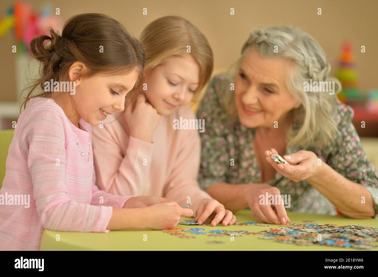Portrait der Großmutter mit kleinen Enkelinnen sammeln Puzzle Stockfoto