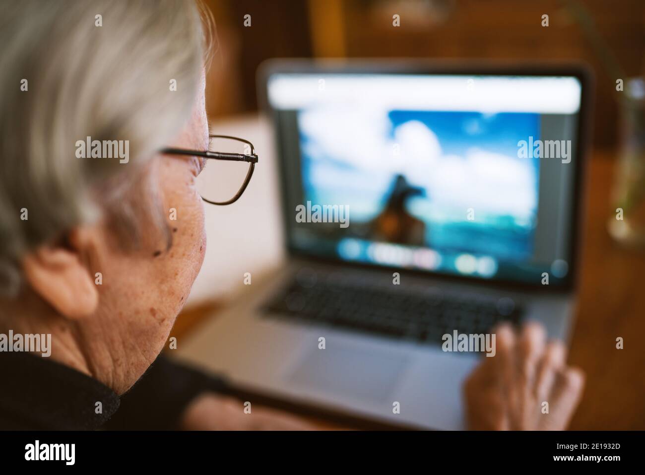 Nahaufnahme einer älteren Frau, die einen Laptop benutzt und Fotos überprüft. Stockfoto