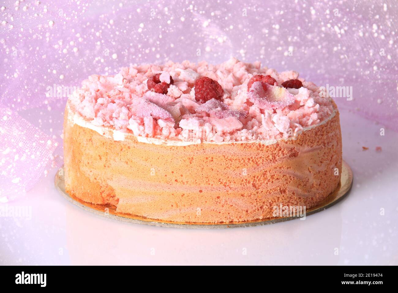 Ein rosa Kuchen mit Baiser bröckelt, Himbeeren, und zuckerhaltigen Rosenblätter. Stockfoto