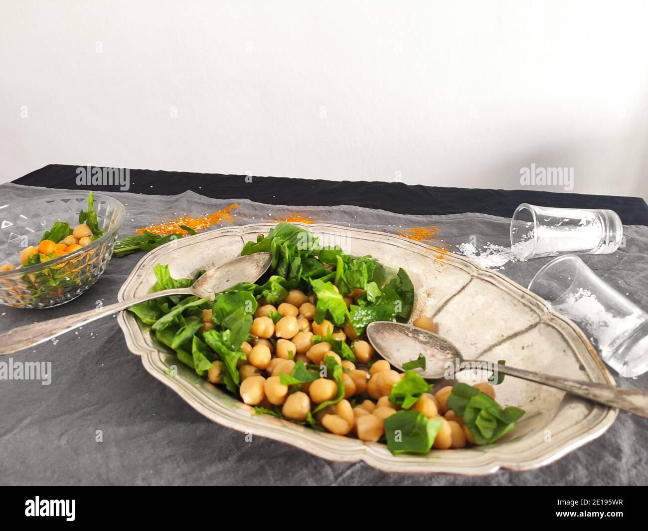 Kichererbsen und frischer Spinatsalat in einem silberovalen Tablett Stockfoto