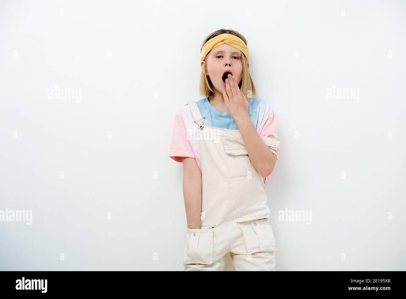 Junge blonde Mädchen gähnt und bedeckt ihren Mund mit der Hand Stockfoto