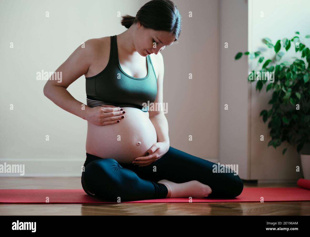 Schwangere junge Frau Workout Yoga zu Hause Stockfoto