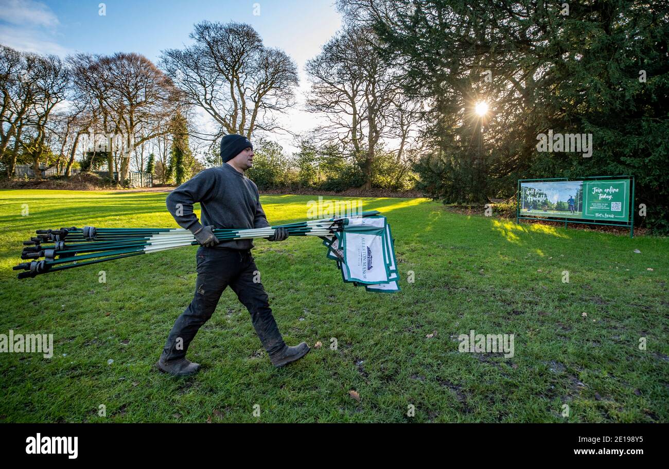 Der grüne Chefkeeper Richie Shields räumt am Morgen, nachdem Premierminister Boris Johnson weitere Maßnahmen im Rahmen einer Sperre in England ergriffen hatte, um die Ausbreitung des Coronavirus zu stoppen, die Flaggen vom Golfplatz des Golfclubs Allerton Manor in Liverpool. Stockfoto