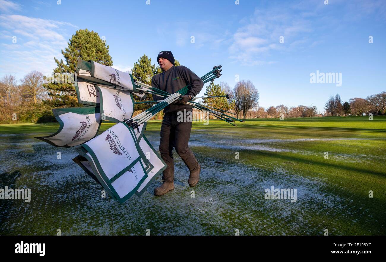 Der grüne Chefkeeper Richie Shields räumt am Morgen, nachdem Premierminister Boris Johnson weitere Maßnahmen im Rahmen einer Sperre in England ergriffen hatte, um die Ausbreitung des Coronavirus zu stoppen, die Flaggen vom Golfplatz des Golfclubs Allerton Manor in Liverpool. Stockfoto