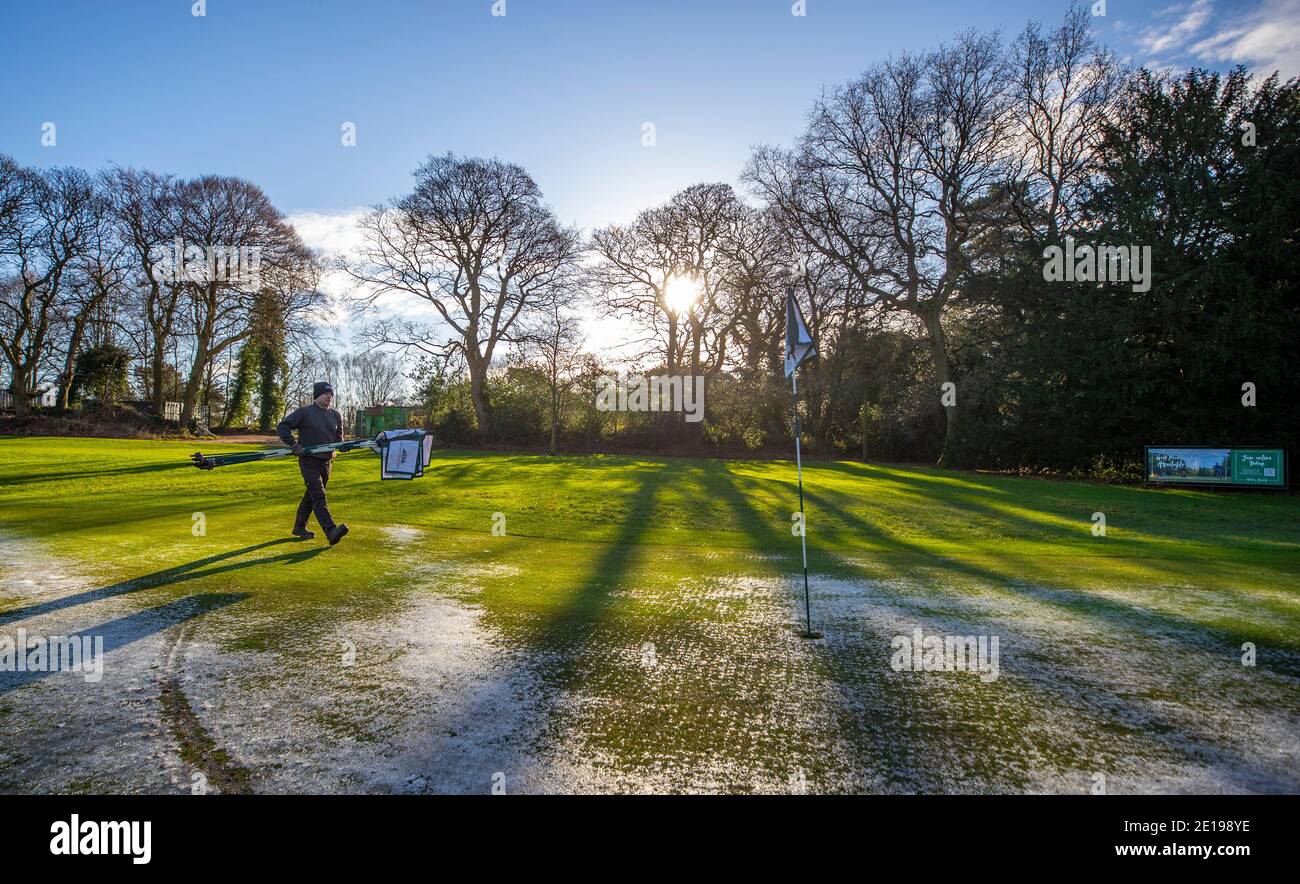 Der grüne Chefkeeper Richie Shields räumt am Morgen, nachdem Premierminister Boris Johnson weitere Maßnahmen im Rahmen einer Sperre in England ergriffen hatte, um die Ausbreitung des Coronavirus zu stoppen, die Flaggen vom Golfplatz des Golfclubs Allerton Manor in Liverpool. Stockfoto