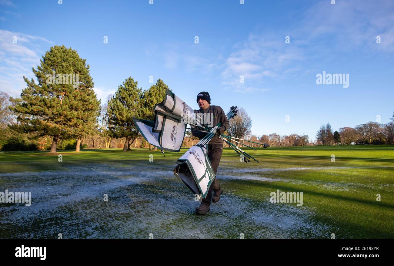 Der grüne Chefkeeper Richie Shields räumt am Morgen, nachdem Premierminister Boris Johnson weitere Maßnahmen im Rahmen einer Sperre in England ergriffen hatte, um die Ausbreitung des Coronavirus zu stoppen, die Flaggen vom Golfplatz des Golfclubs Allerton Manor in Liverpool. Stockfoto