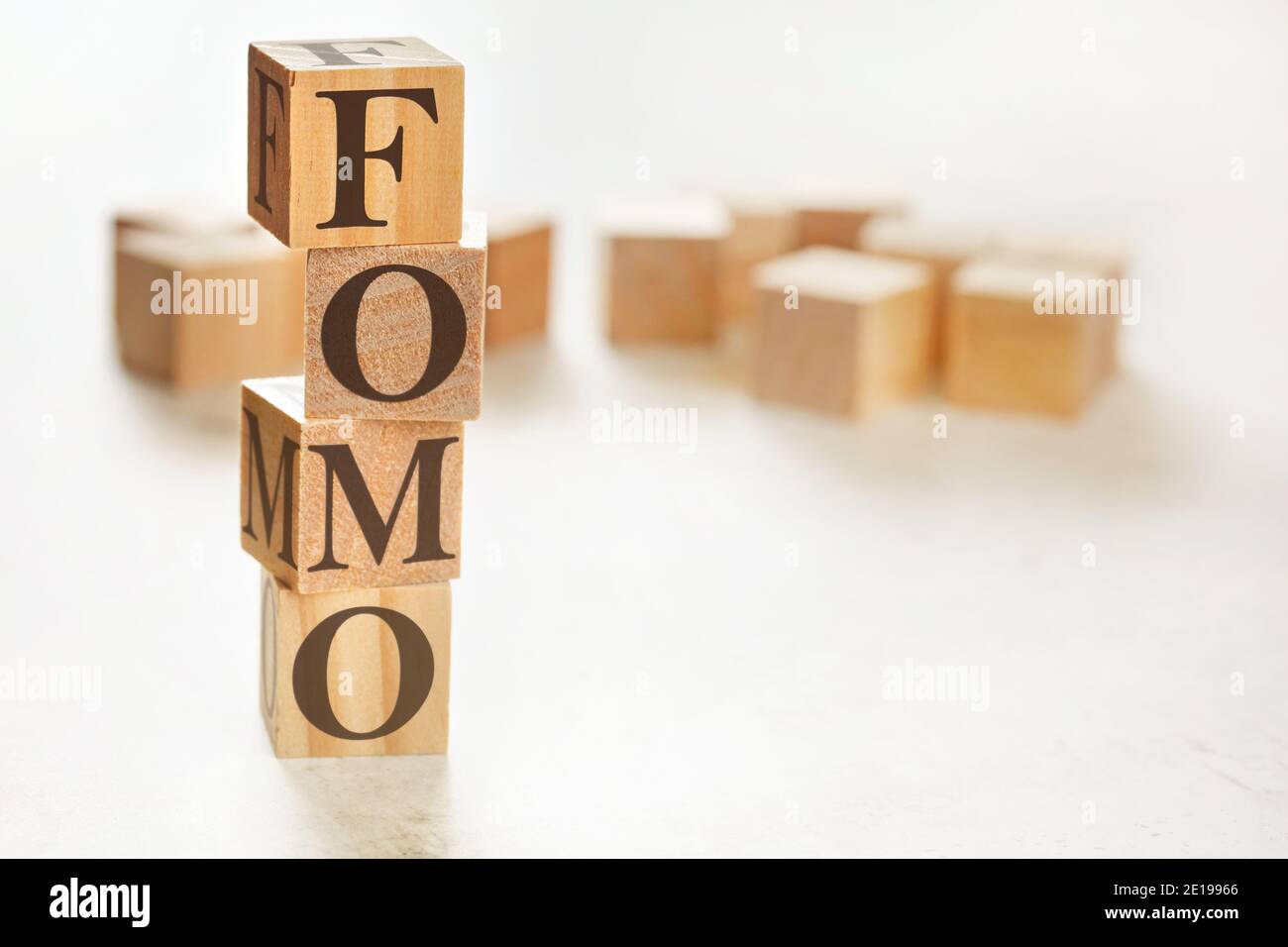 Vier Holzwürfel im Stapel angeordnet mit Buchstaben FOMO (was Angst vor dem Verfehlen bedeutet) darauf, Platz für Text / Bild in der rechten unteren Ecke Stockfoto