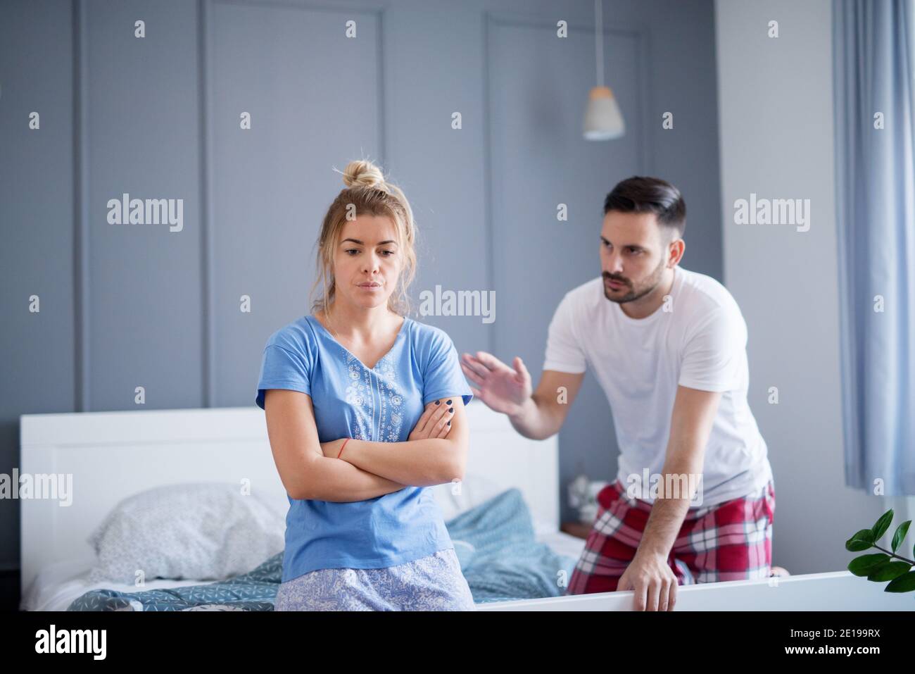 Besorgt und traurig junge Frau sitzt am Rand des Bettes und hört ihrem Mann reden über Probleme. Stockfoto