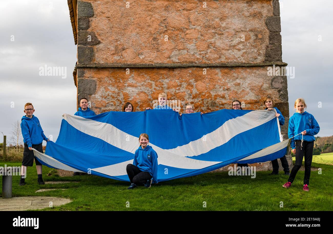 Schulkinder feiern den St. Andrew's Day mit einer riesigen Saltire-Flagge, Athelstaneford Heritage Centre, East Lothian, Schottland, Großbritannien Stockfoto