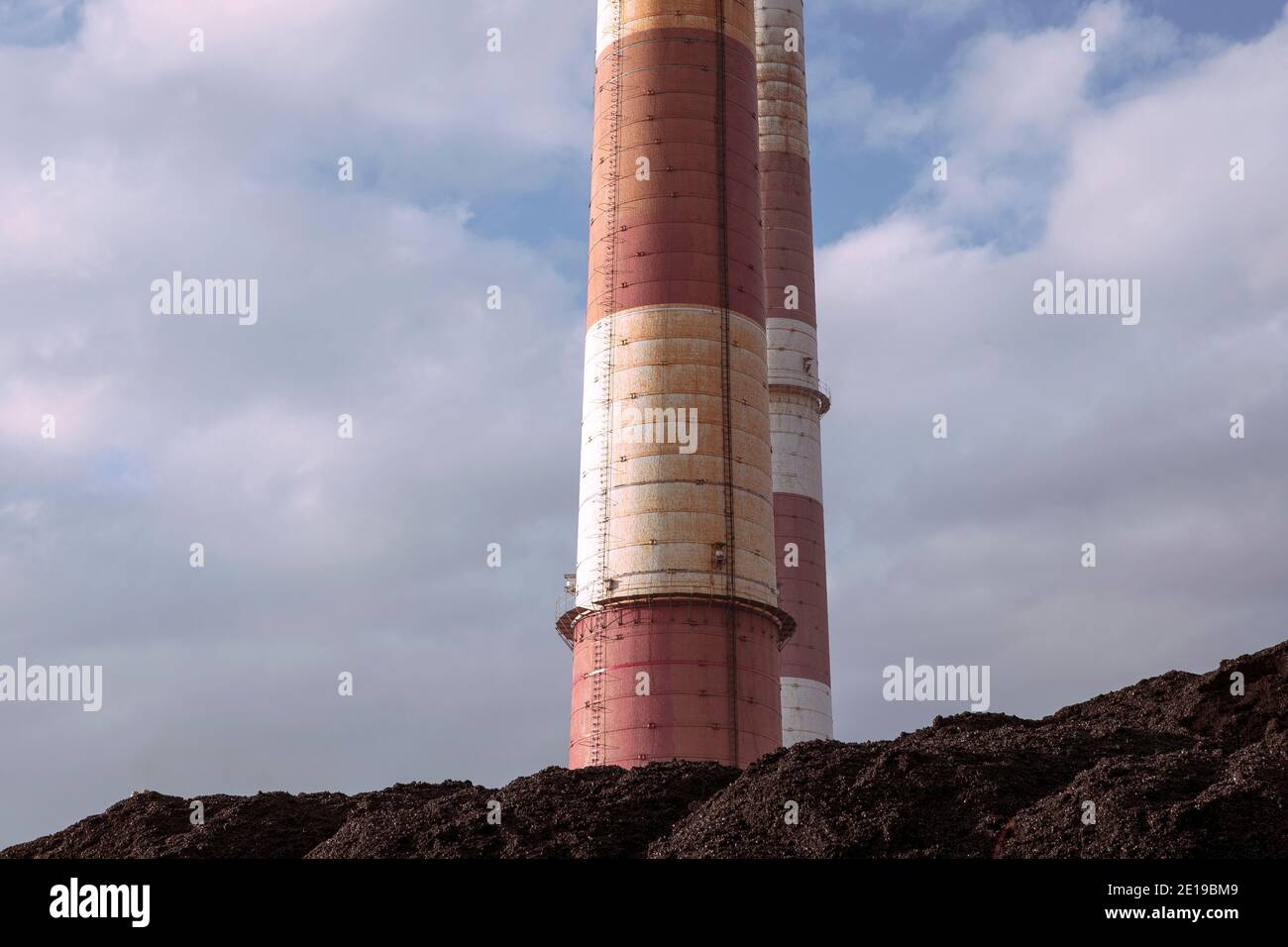 Kohlehaufen, natürliche schwarze Kohle mit industriellen Schornsteinen und blauen Wolken Himmel. Industrieller Hintergrund. Globale Erwärmung, CO2-Emissionen, Kohlenenergieprobleme. Stockfoto