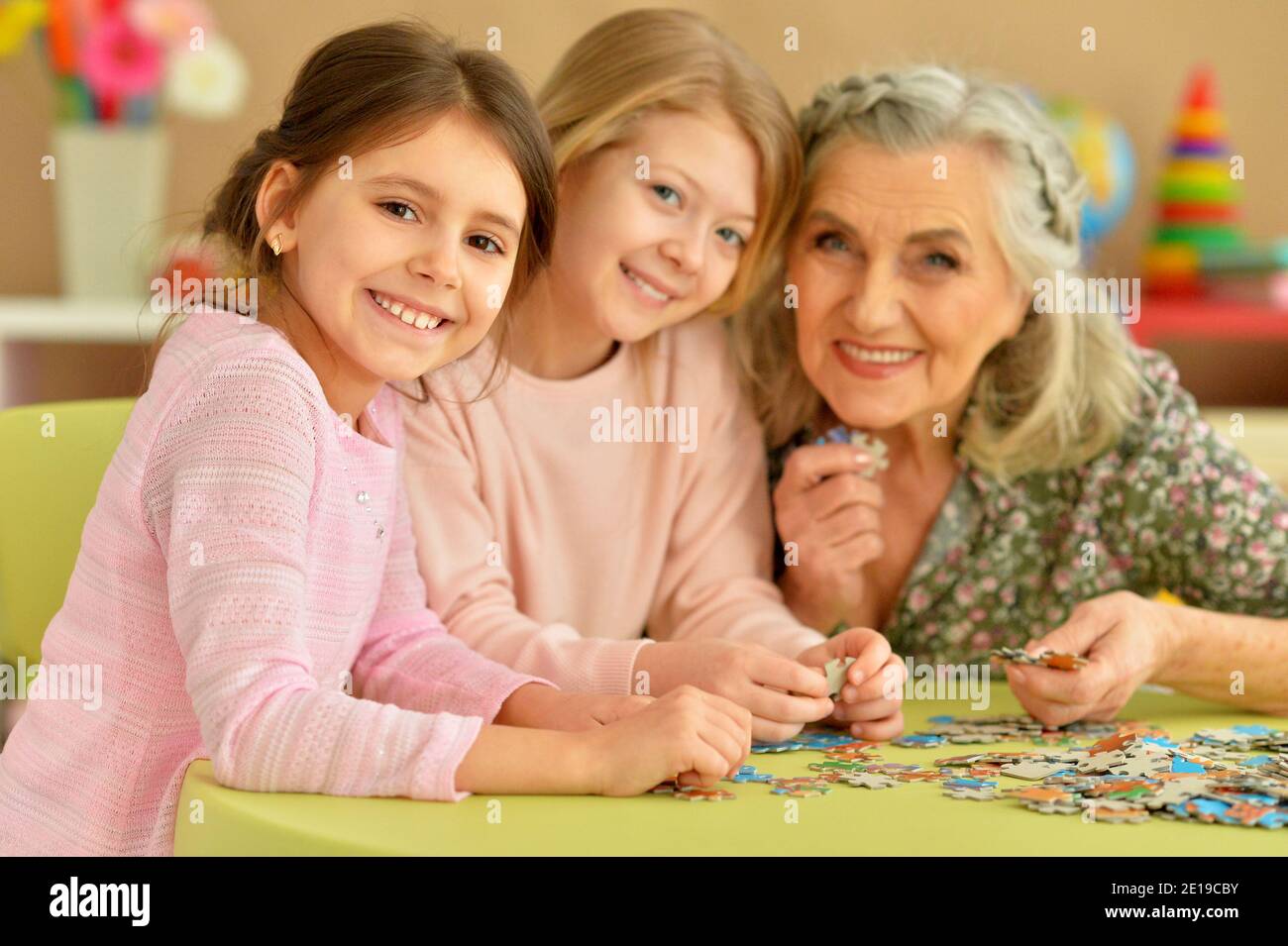Portrait der Großmutter mit kleinen Enkelinnen sammeln Puzzle Stockfoto