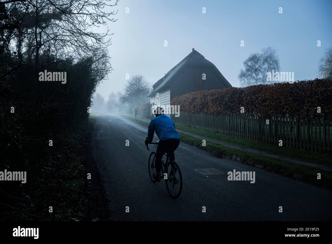 Radfahrer auf einer Radtour, mit seinem Fahrrad auf einem Radrennen, Rennen entlang einer ländlichen engen Landstraße in dichtem Nebel und Nebel bei nebligen nebligen Wetter auf englischen Straßen, Hinterstraßen Straßen in England, Großbritannien Stockfoto