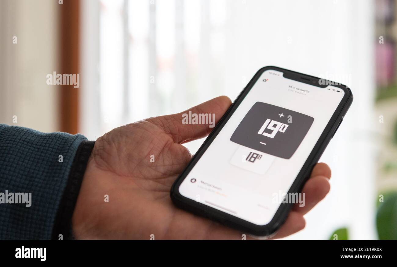Mann, der die Heizung seines Hauses mit einer Anwendung steuert Am Telefon Stockfoto