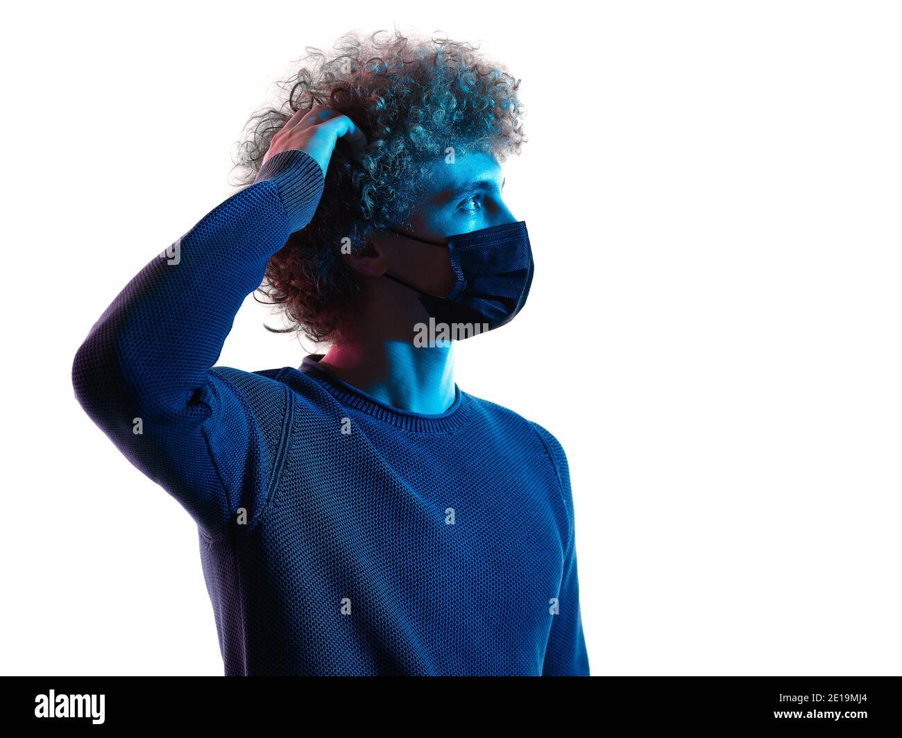 Ein kaukasischer junger Mann, der eine Maske trägt und denkt, dass er schaut Oben im Studio Schatten isoliert weißen Hintergrund Stockfoto