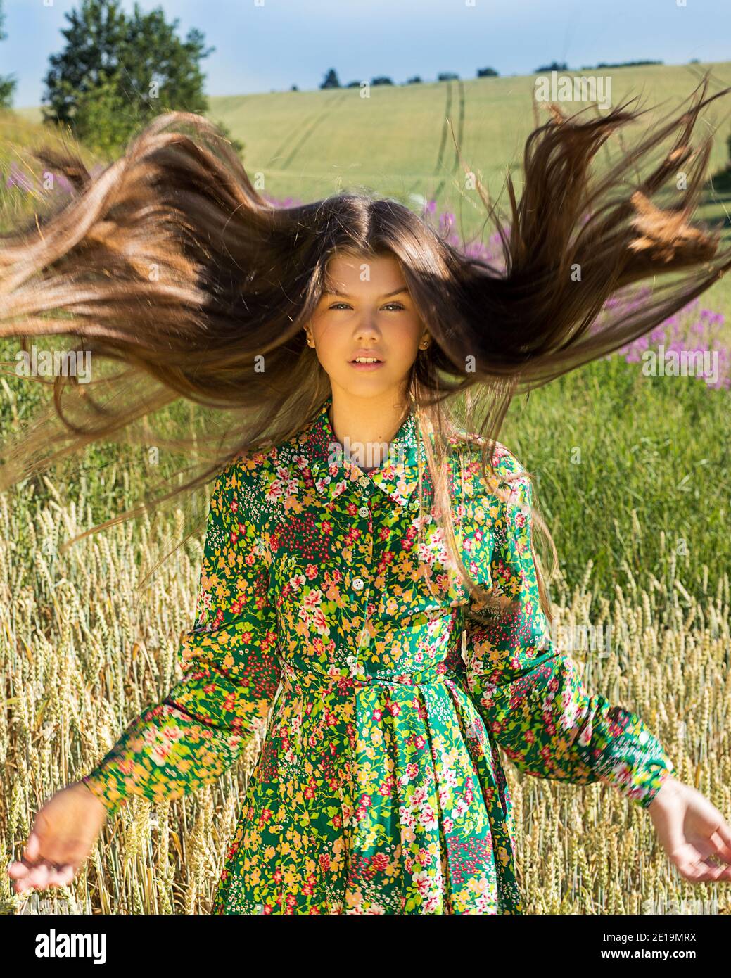 Natürliche schöne Mädchen mit fliegenden Haaren im Wind auf grün blühenden Wiese. Stockfoto