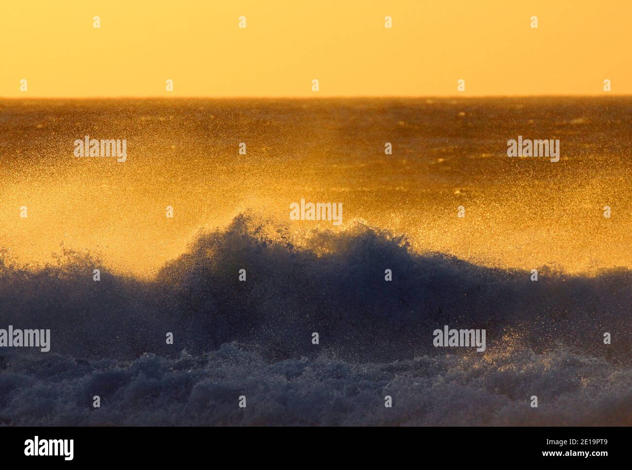 Surfen Sie an der Küste von Kapstadt in Südafrika Mit Blick vom Strand auf das Meer mit Bruch Wellen während der goldenen Stunde vor Sonnenuntergang Stockfoto