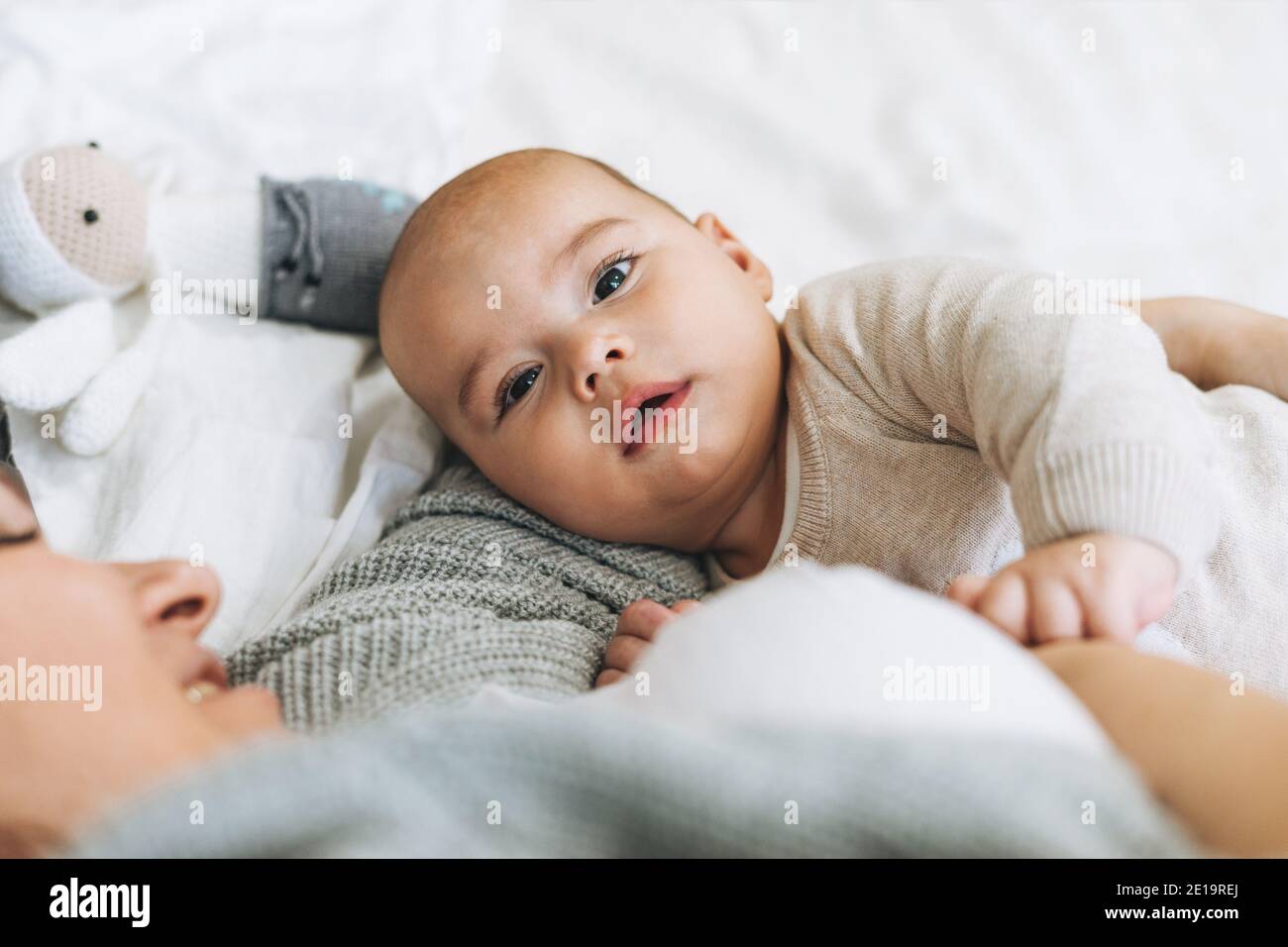 Junge Mutter mit niedlichen Baby junge, Mutter Brust füttert Baby auf dem Bett, natürliche Töne Stockfoto