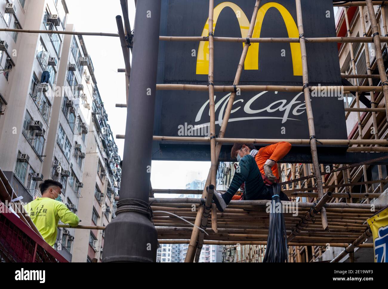 Bauarbeiter werden gesehen, wie sie ein amerikanisches multinationales Fast-Food-Hamburger-Restaurantkette McDonald's und McCafe Schild in Hongkong sehen. Stockfoto