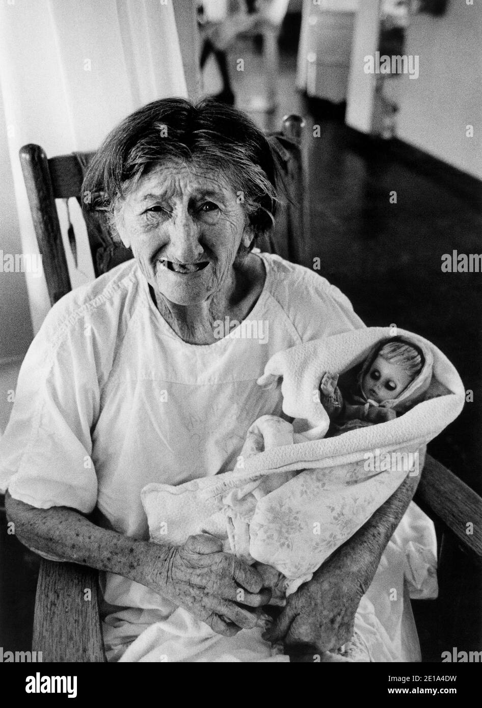 Alte Frau mit Demenz hält eine Puppe in einem South Florida Pflegeheim. Stockfoto
