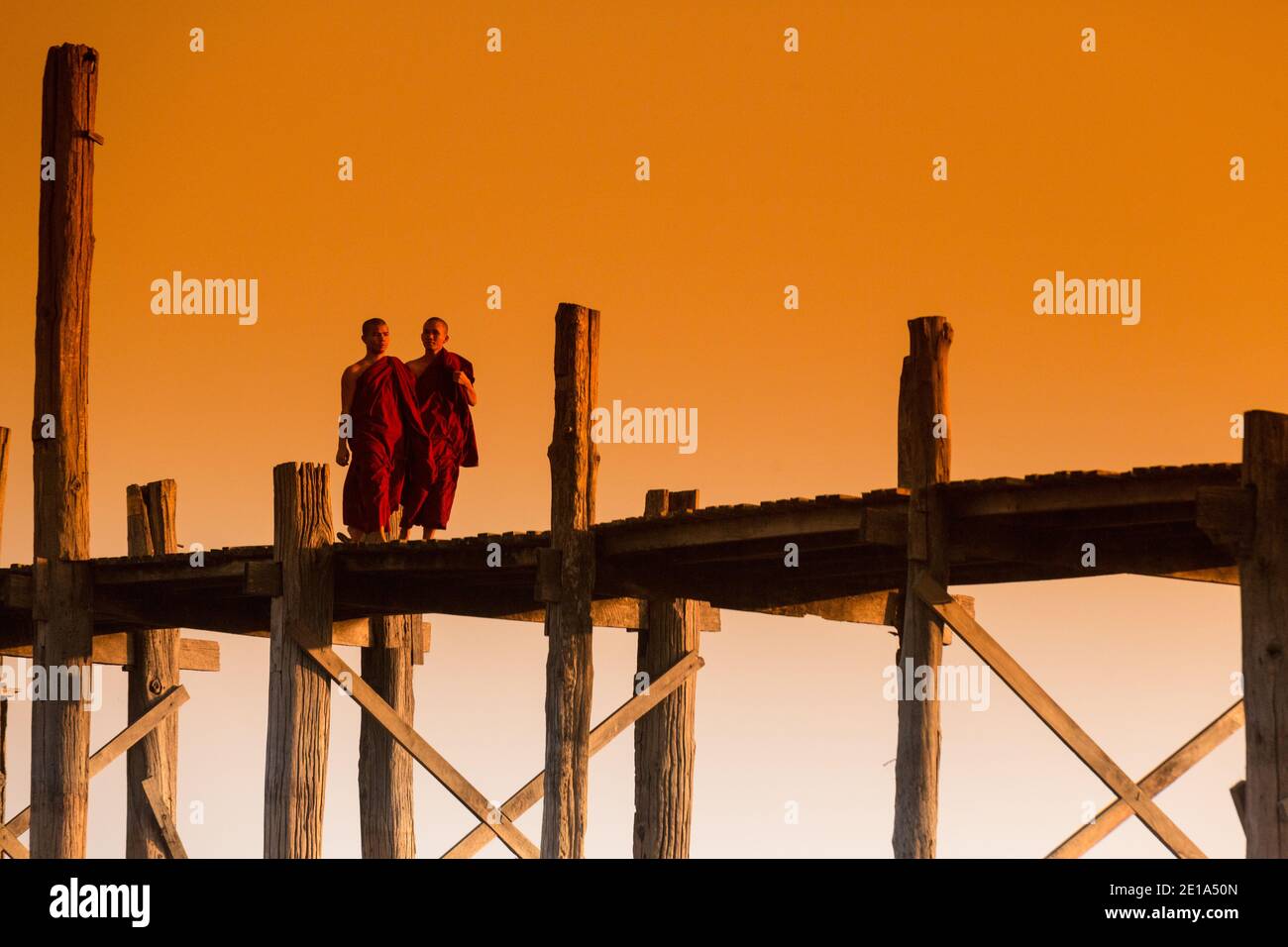Mönche überqueren U Bein's Bridge bei Sonnenuntergang Stockfoto