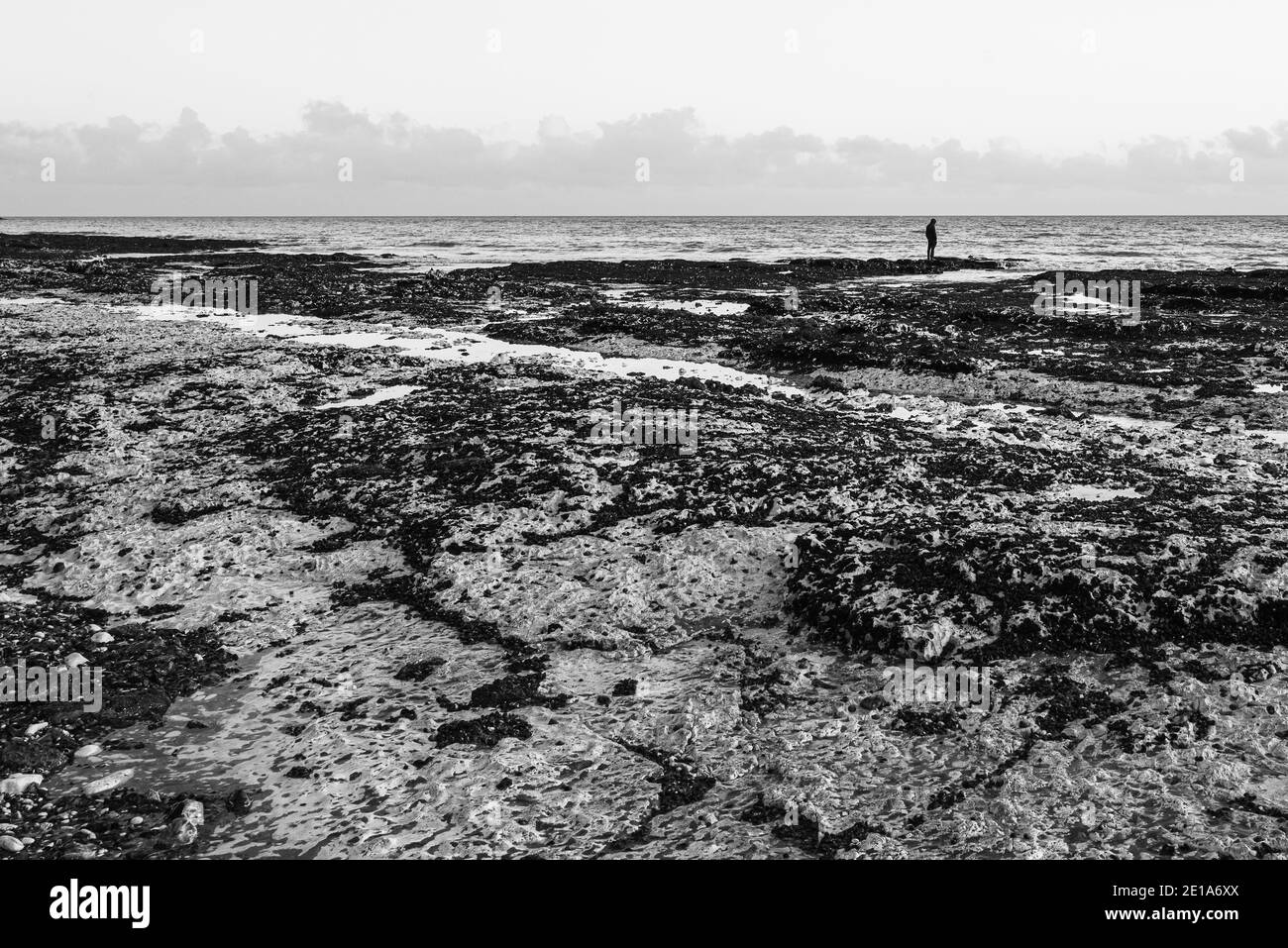 Schwarz-Weiß-Bild einer einzelnen Person auf einem Kreide Felsen Strand stehen. Es hat ein Gefühl der Einsamkeit, und möglicherweise Traurigkeit oder Verzweiflung, mit Kopie spac Stockfoto