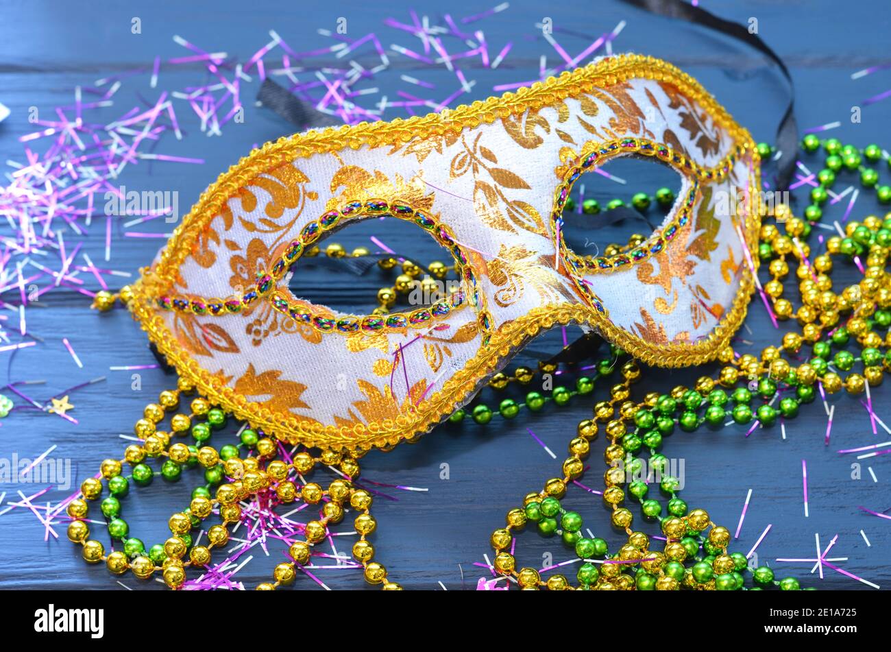 Mardi Gras Maske und Perlen auf einem Holzhintergrund. MADI Gras Karnevalszubehör, Konfetti, Festliche, venezianische oder Karnevalsmaske. Maskerade Stockfoto