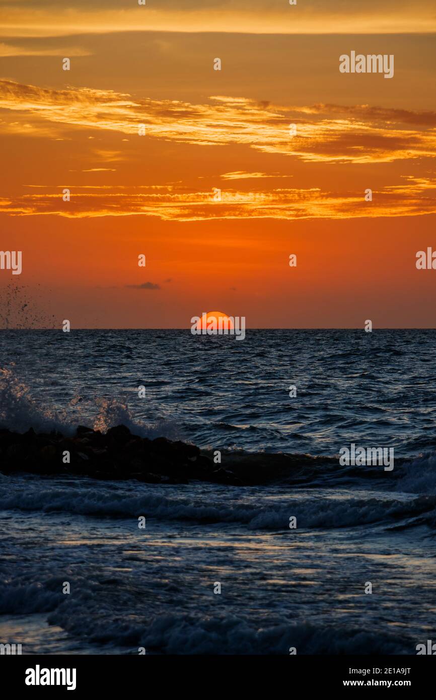 Ein schöner Anblick einer tropischen Strandlandschaft, die Sonne untergeht in einem wundervollen und bunten Sonnenuntergang Stockfoto