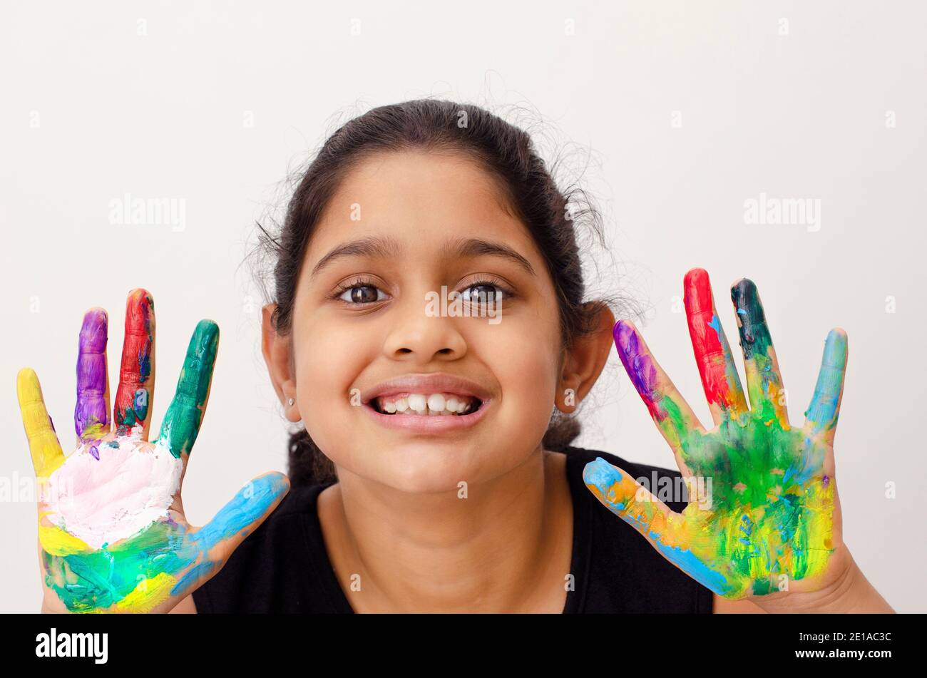Porträt eines glücklichen und lächelnden indischen Kind spielen und genießen mit Farben in den Fingern. Stockfoto